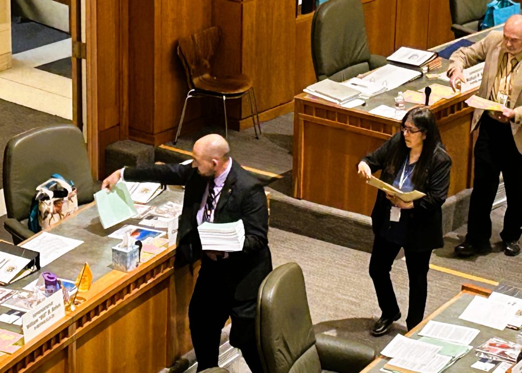 Staff pass out copies of HB 2/3 to legislators' workspaces before the House session January 31, 2024.